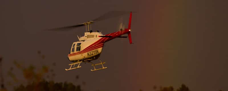 Bell 206 JetRanger in flight by a rainbow